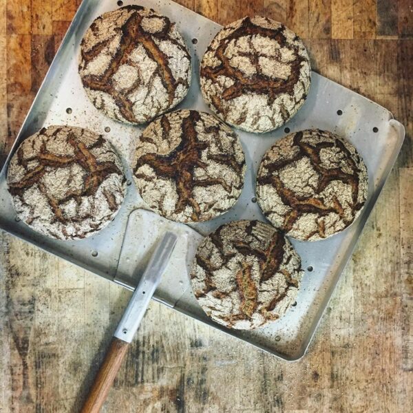 Vier Bio-BIO-SYLTER LICHTKORN-ROGGEN BROT auf einem Metalltablett mit einem Messer.