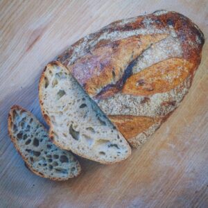 Ein Laib BIO-SYLTER SAUERTEIGBROT auf einem Holztisch.