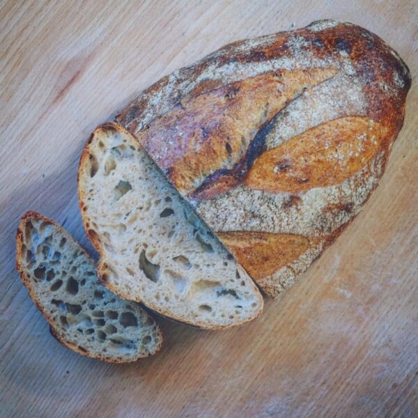 Ein Laib BIO-SYLTER SAUERTEIGBROT auf einem Holztisch.